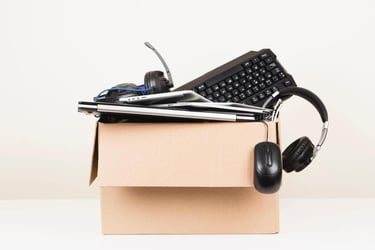 box of used and discarded technology including headphones and pc keyboard