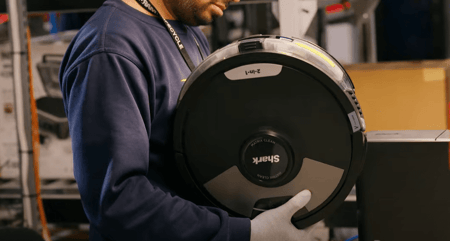 Returns management technician handles robot vacuum cleaner