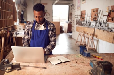 carpenter in workshop using refurbished laptop